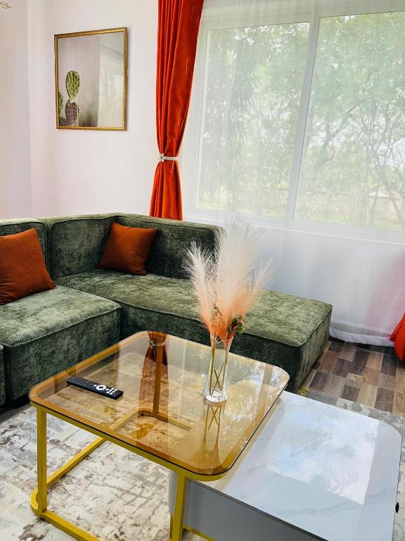 a living room with a green couch and a glass table at Tiny Card Milimani Homes in Kisumu