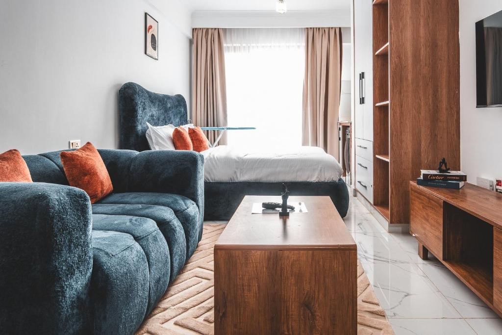 a living room with a blue couch and a bed at Kilimani Chic Studio in Nairobi