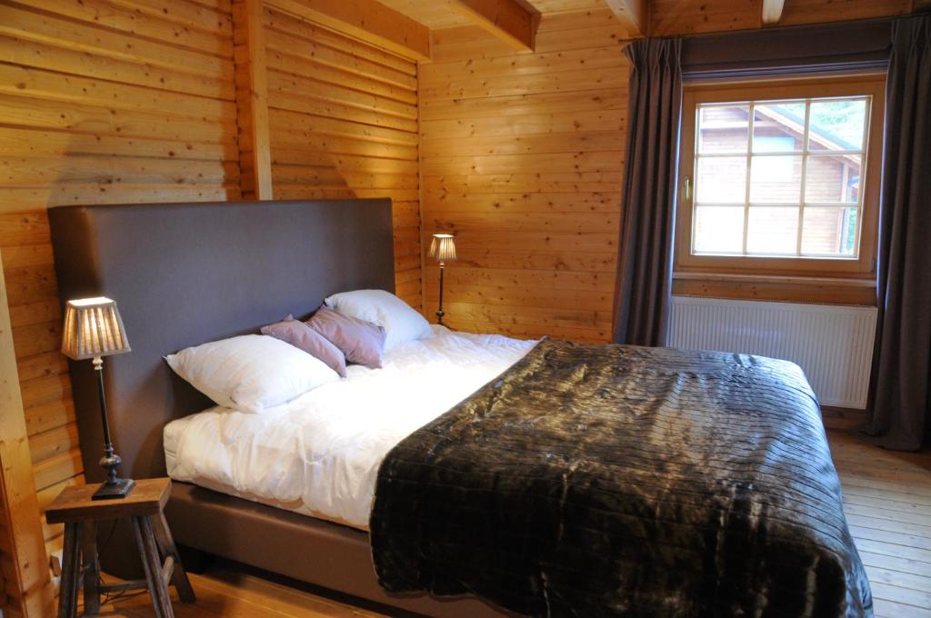 een slaapkamer met een groot bed in een houten kamer bij La Grande Ourse in Durbuy