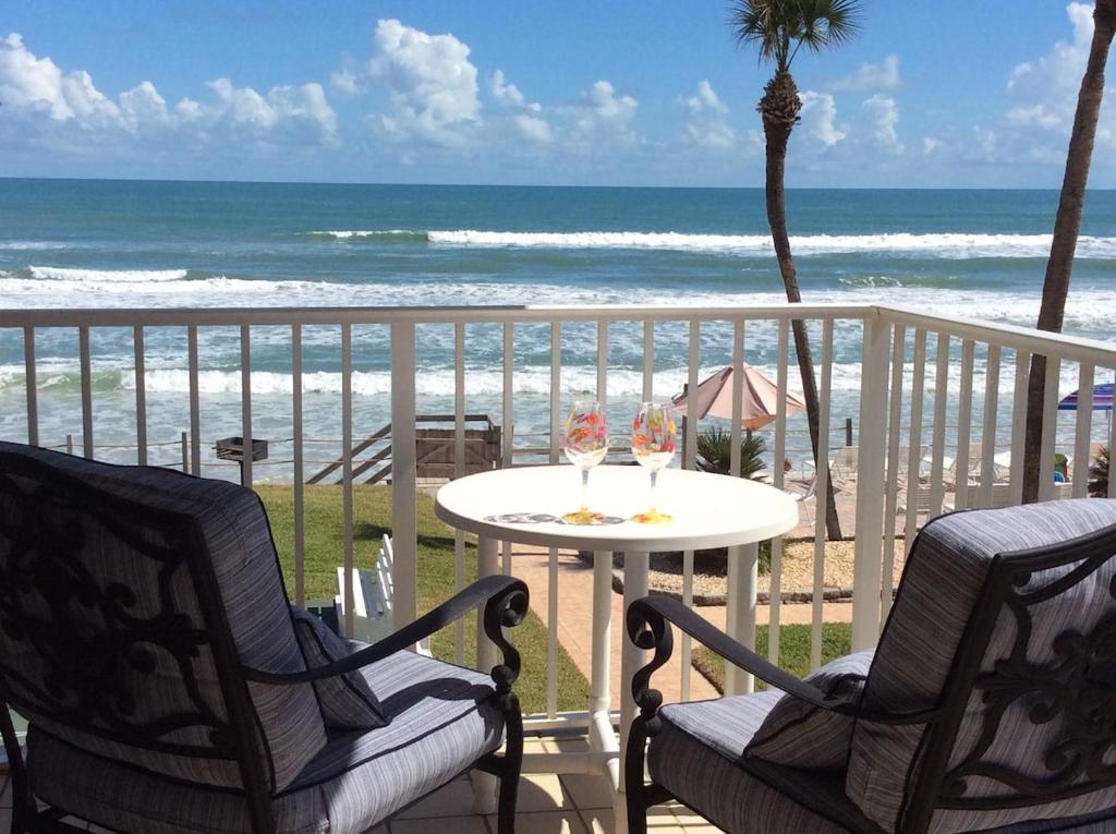 un balcon avec deux chaises et une table et la plage dans l'établissement Refreshing oceanfront gem Remarkable sunrises, à New Smyrna Beach