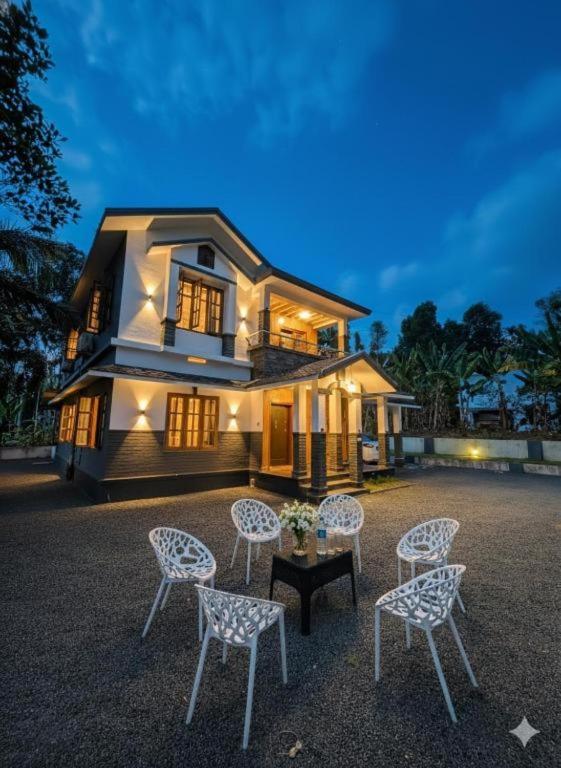 a house with chairs and a table in front of it at Windgram Homestay in Ambalavayal
