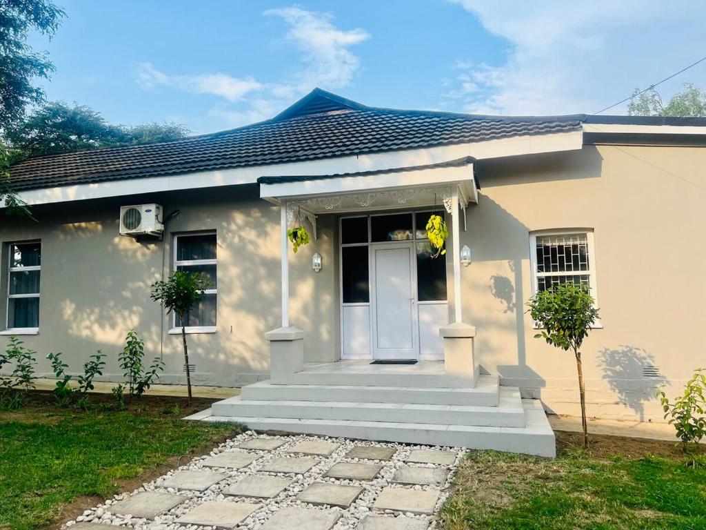 una casa bianca con una porta bianca e scale di The Townhouse Mkhondo a Piet Retief
