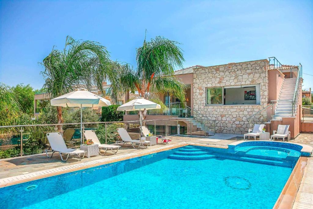 a swimming pool with chairs and umbrellas next to a house at Villa Galene in Polis Chrysochous