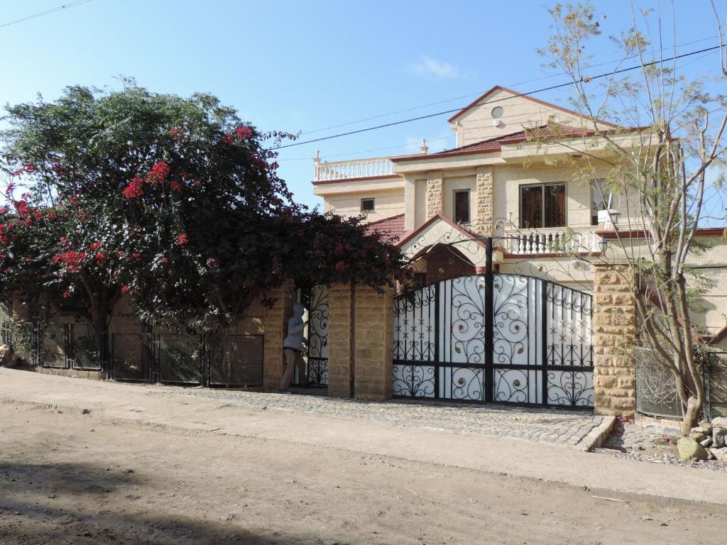 uma casa com um portão em frente em Asimba Guest House em Mekʼelē