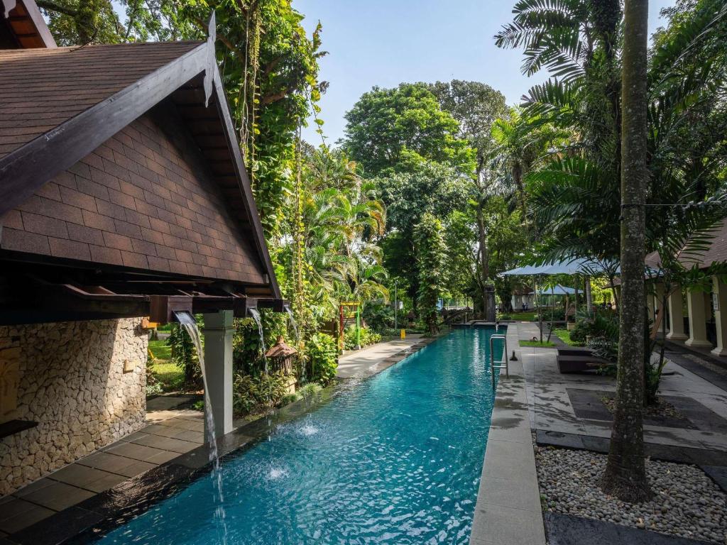 a swimming pool in a resort with a waterfall at Novotel Bogor Golf Resort in Bogor
