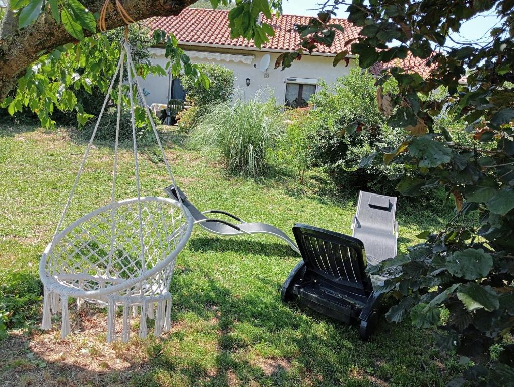 a swing and a chair in a yard at La Cabane du Berger & son terrain de pétanque in Torsiac