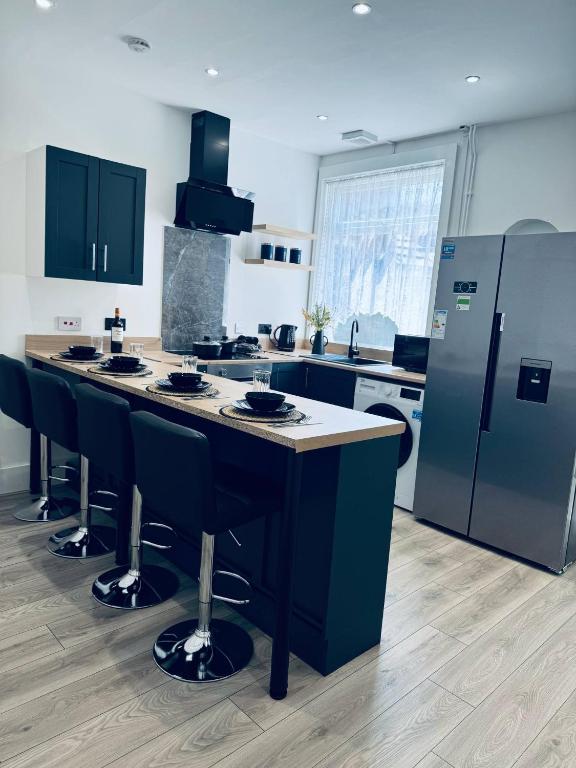 a kitchen with a counter with chairs and a refrigerator at Sterling House - by Eazystays in Crewe
