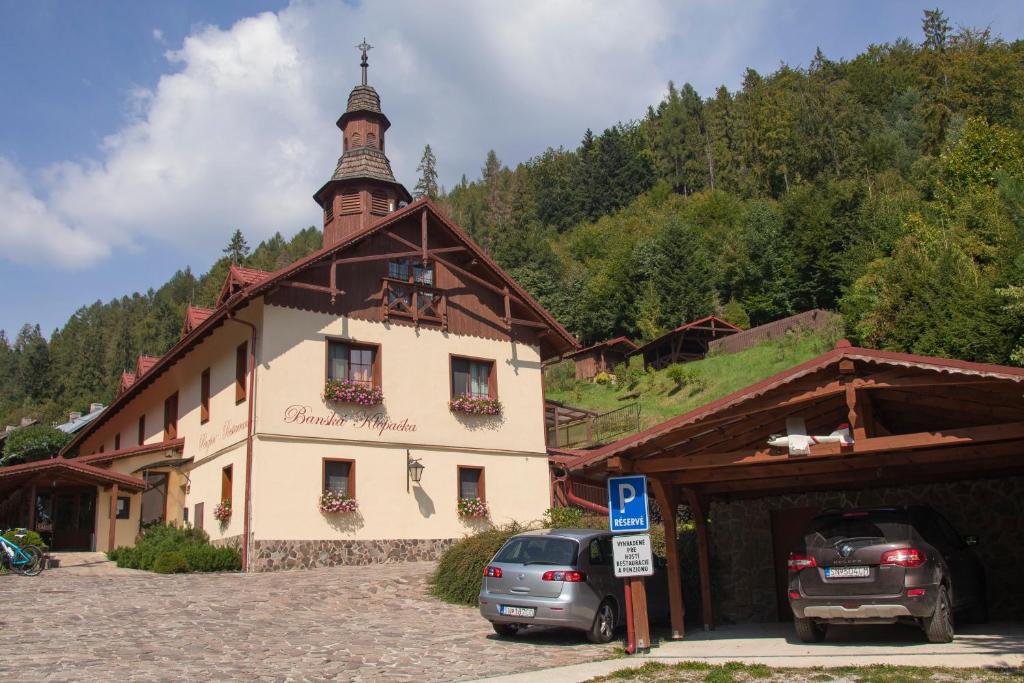 un bâtiment avec des voitures garées devant lui dans l'établissement Penzión Banská Klopačka, à Hnilčík