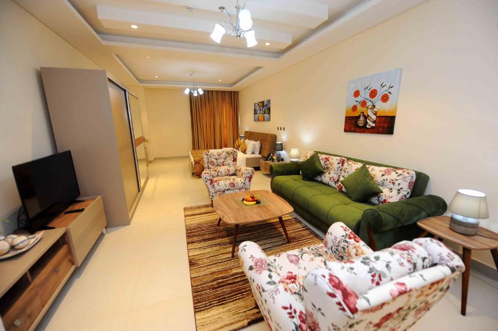 a living room with a green couch and a tv at Al Mansour Park Inn Hotel&Apartment in Doha