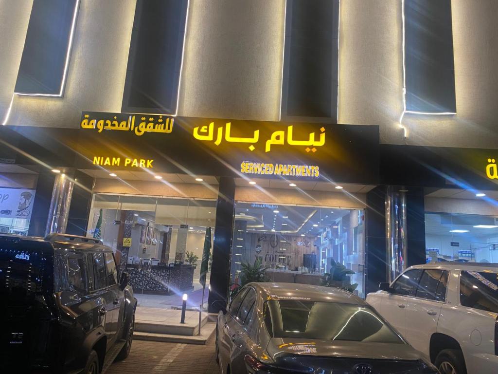 Twee auto's geparkeerd voor een winkel in een herenpark. bij شقق نيام بارك للشقق المخدومه in Rafha