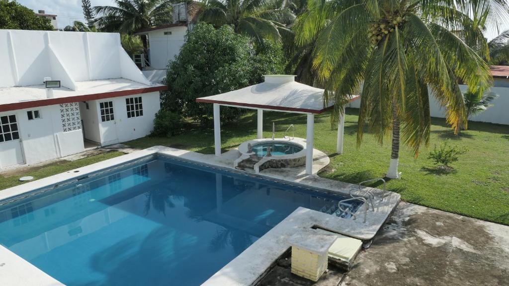 a swimming pool with a gazebo next to a house at Alojamiento con alberca privada y jardín grande in Tecolutla