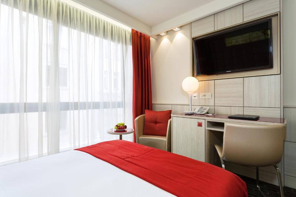 a hotel room with a bed and a desk and a television at Hotel St.Gotthard in Zürich