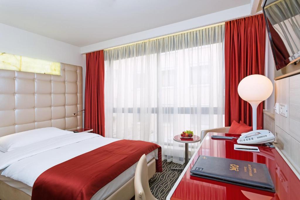a hotel room with a bed and a desk with a phone at Hotel St.Gotthard in Zürich