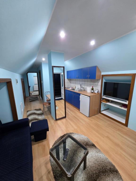 a large living room with blue cabinets and a kitchen at D&D Apartment in Koceljevo