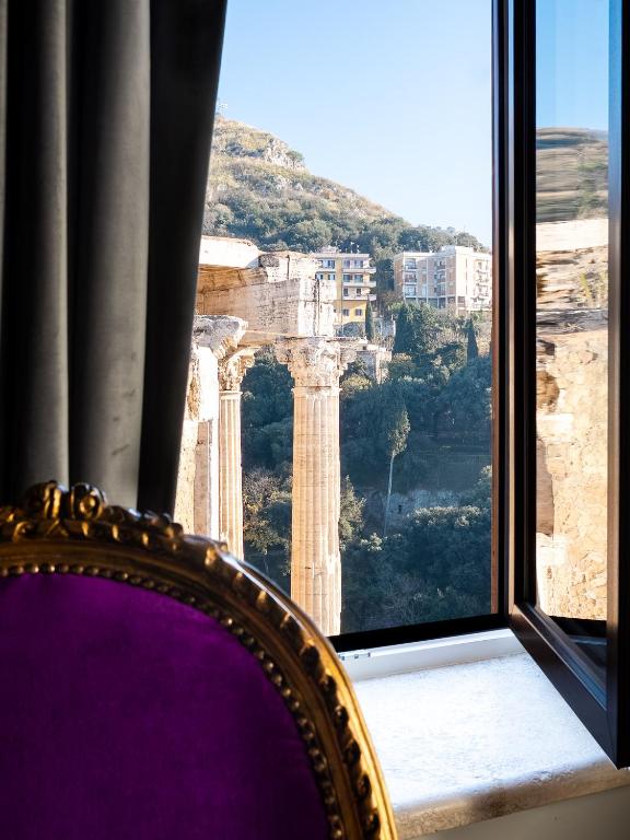 a chair sitting in front of a window with a view at Locanda Sibilla Luxury Suites in Tivoli