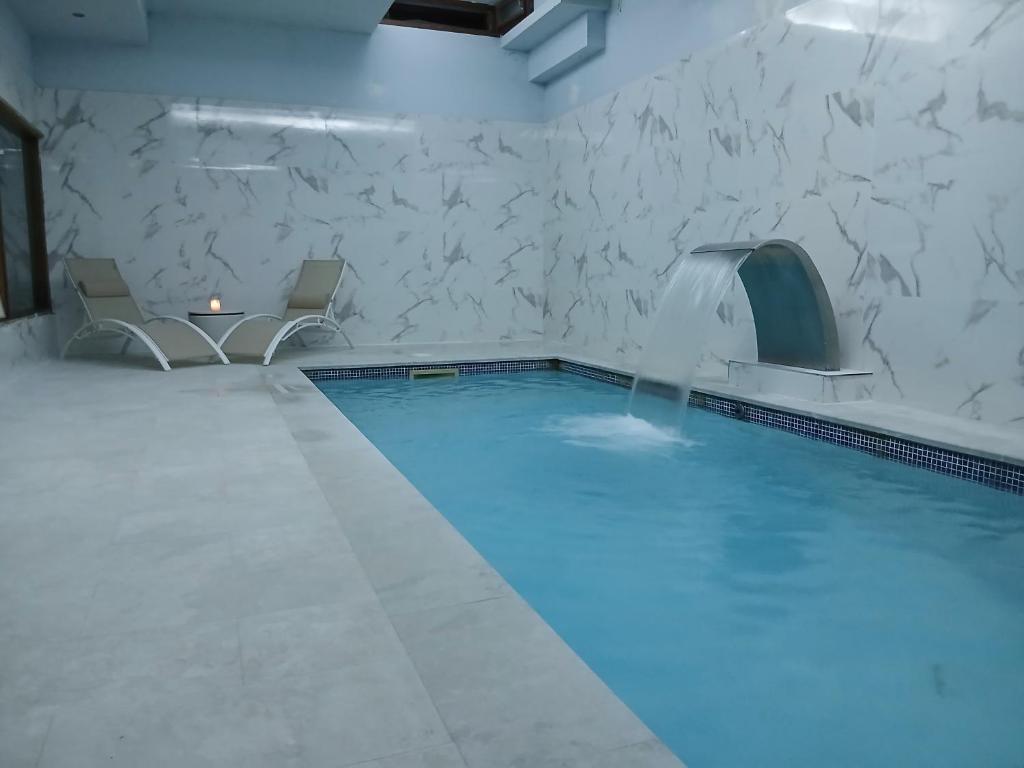 une piscine avec deux chaises et une piscine iteratorhaarhaarhaarhaarhaar dans l'établissement LA CASONA Encanto Rural - ApartaHotel SPA Llanes, à Llanes