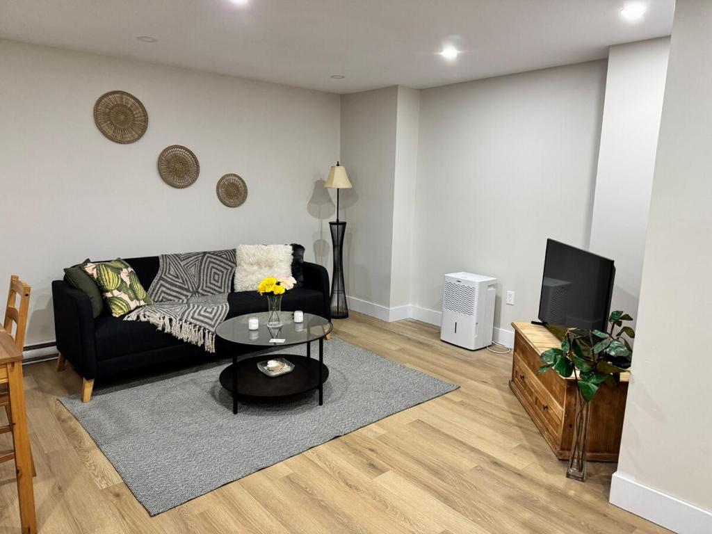 un soggiorno con un divano nero e una TV di New Modern Private Suite Near Champlain Mall a Moncton