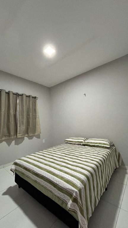 a bedroom with a bed with a striped blanket at Casa de praia Cleo in Luis Correia