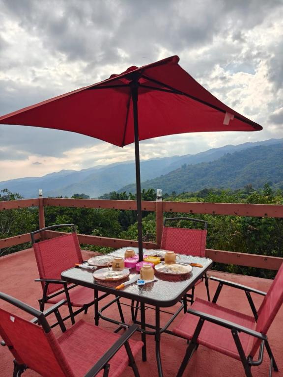a picnic table with a red umbrella on a deck at Cabañas El Amanecer in Cuetzalán del Progreso