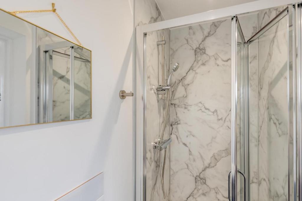 a shower with a glass door next to a mirror at 3 Bed in Georgeham oc-seashe in Georgeham