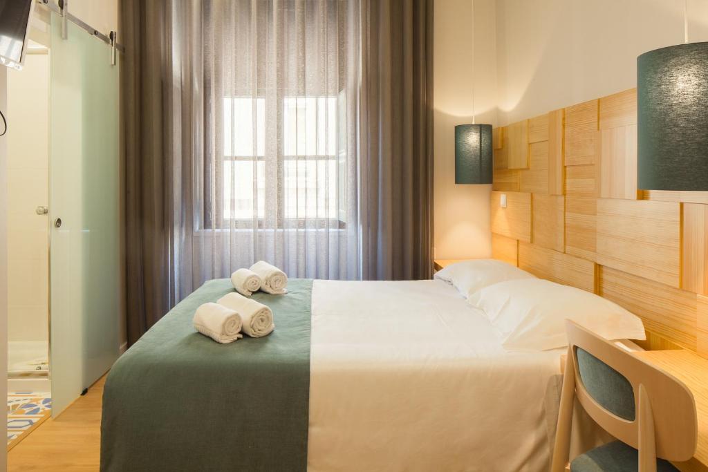 a hotel room with a bed with towels on it at Boavista Guest House in Porto