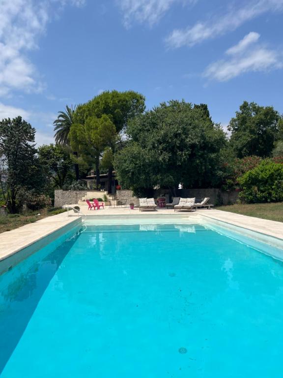 ein großer blauer Pool mit Bäumen im Hintergrund in der Unterkunft Studio au dernier étage d'une bastide grassoise in Grasse