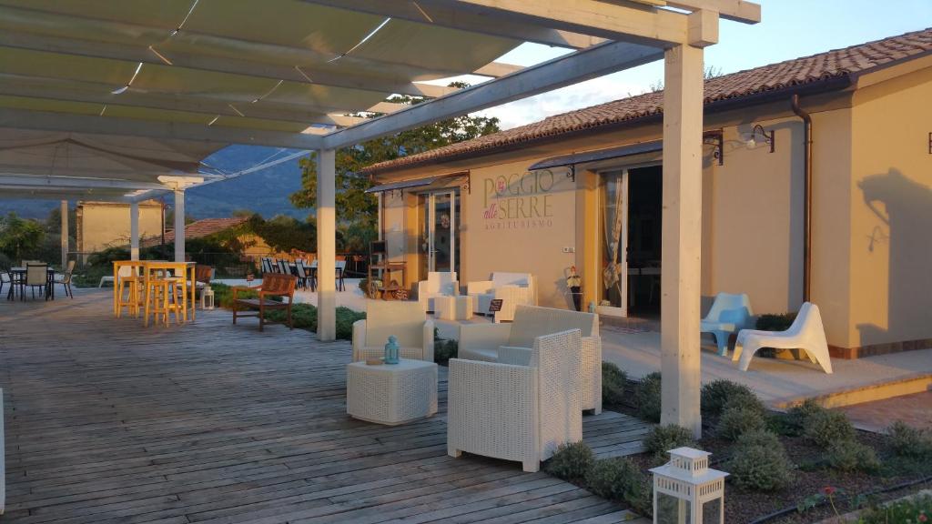 a wooden deck with chairs and tables on a building at Agriturismo Poggio Alle Serre in Gallinaro