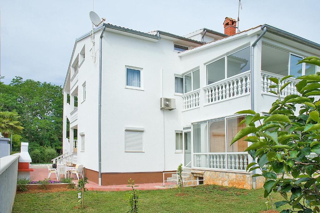 a white house with a balcony and a yard at Apartments SoMi in Poreč