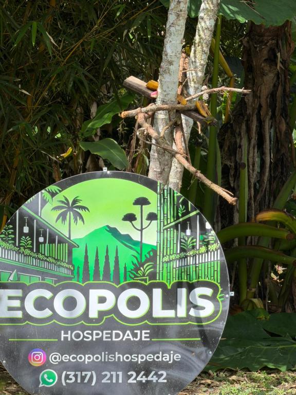 un cartello davanti a un albero con l'immagine di ecocoles di cabaña grande ecopolis hospedaje a El Queremal