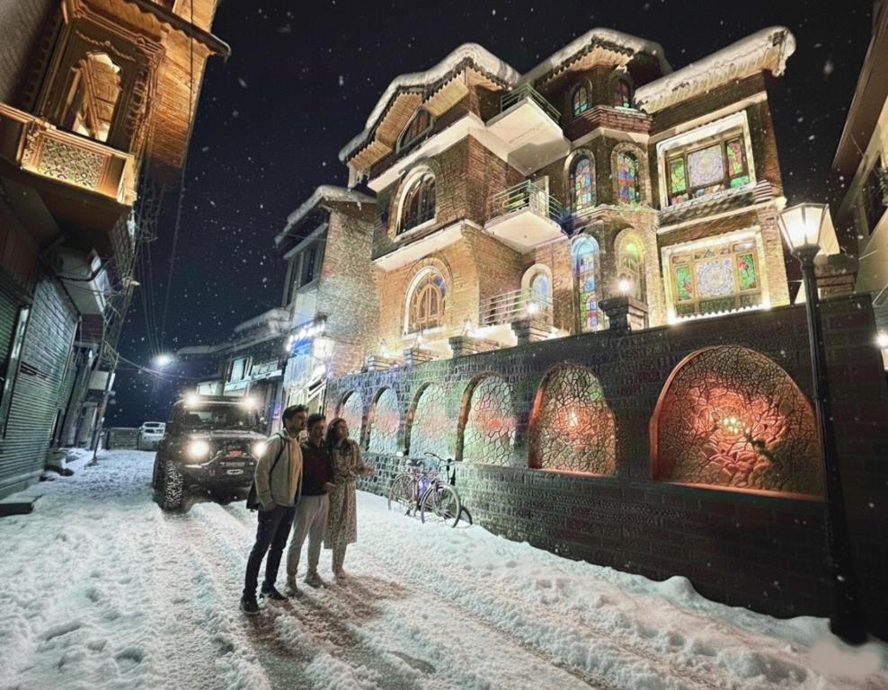 een stel dat in de sneeuw voor een gebouw staat bij Faizzy residency in Srinagar