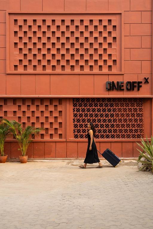 a woman walking in front of a building with a suitcase at ONEOFF X ASSI - A Boutique Homeotel in Varanasi