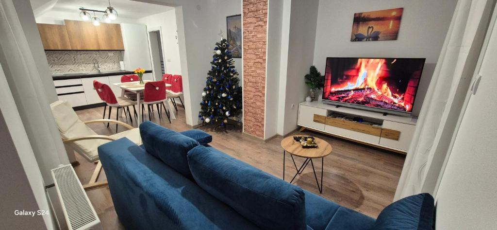 een woonkamer met een blauwe bank en een kerstboom bij Apartman Swans in Otočac