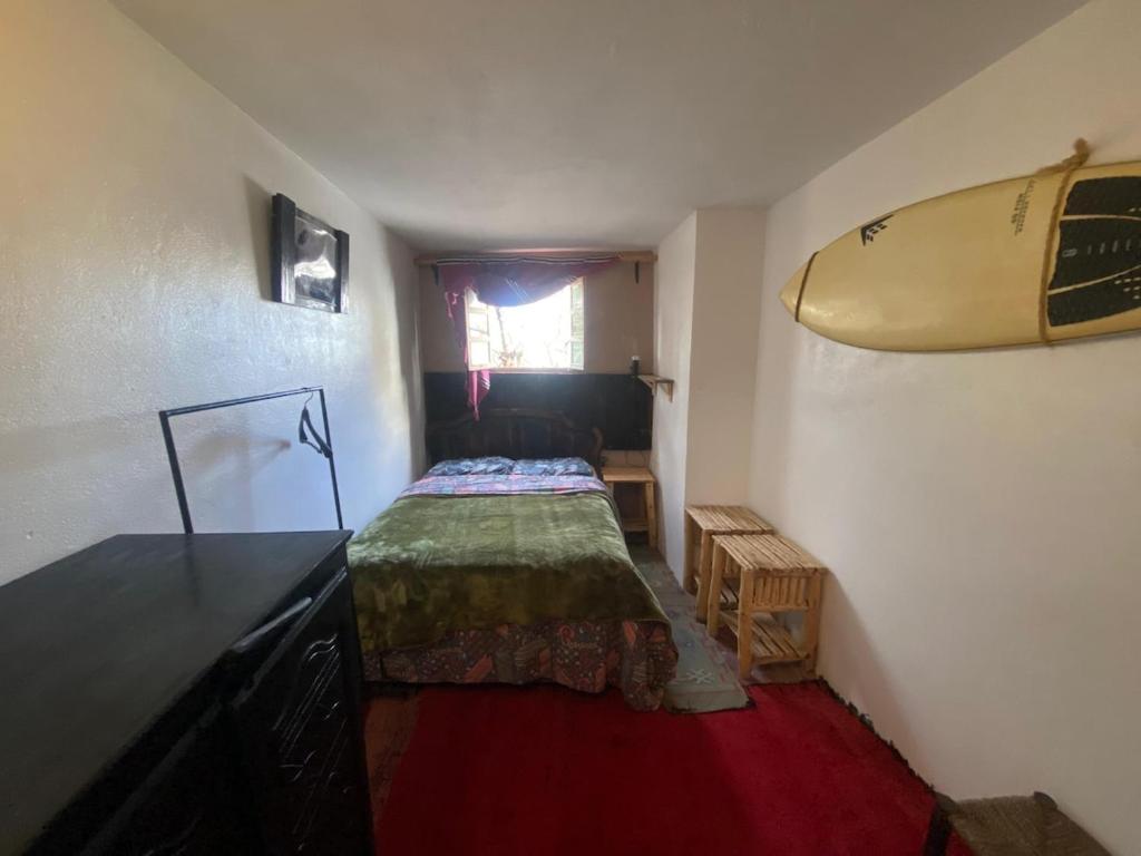 - une chambre avec un lit et une planche de surf sur le mur dans l'établissement Studio Surf House Kaouki, à Sidi Kaouki