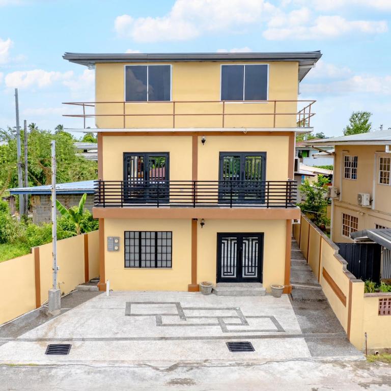 a yellow house with a balcony at The Dorset on Ashby in Chaguanas