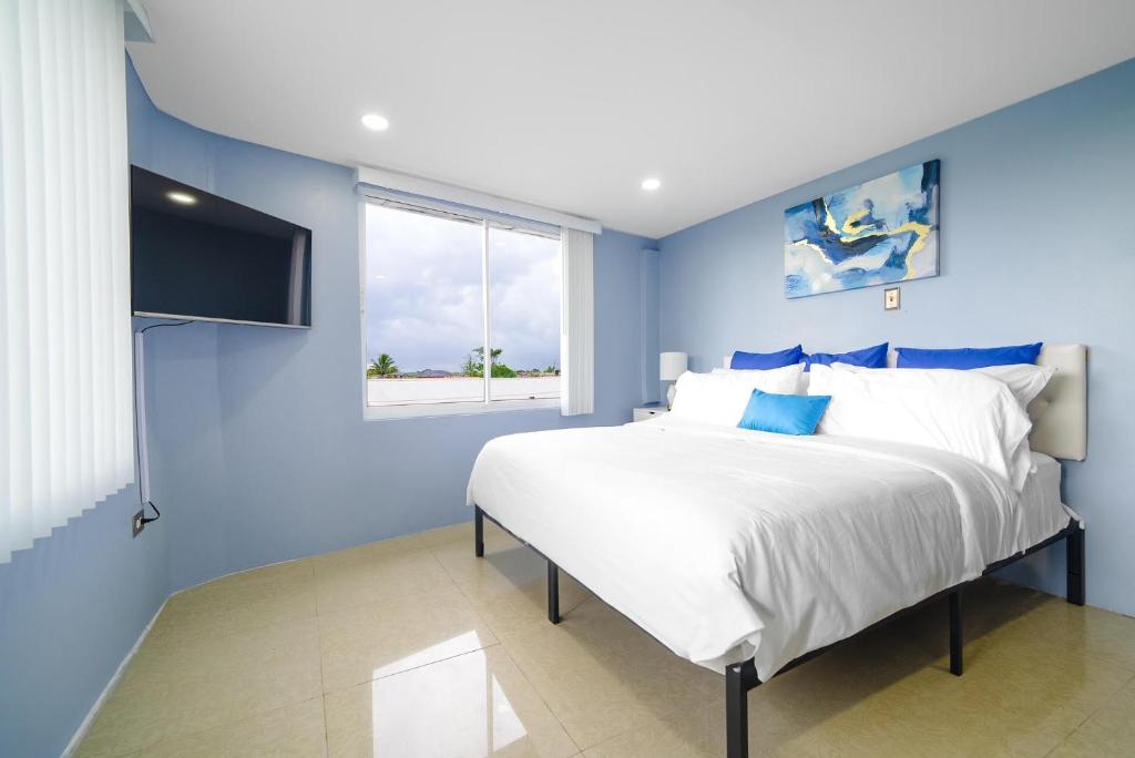 een blauwe slaapkamer met een groot bed en een raam bij The Dorset on Ashby in Chaguanas Village