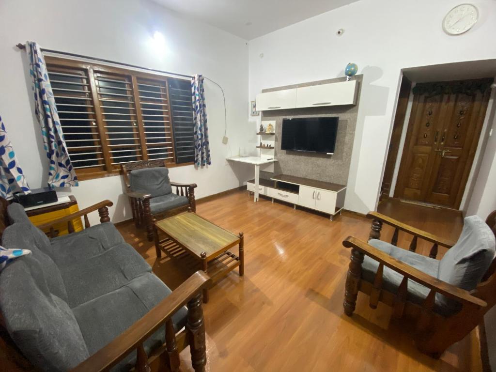 ein Wohnzimmer mit Sofa, Sesseln und Fernseher in der Unterkunft Jk homestay Mysore in Mysore