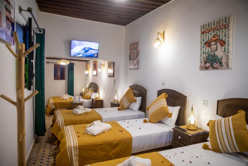a room with three beds and a tv on the wall at Shauala Riad - Where History Lives in Fès