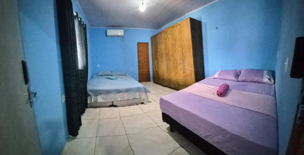 twee bedden in een kamer met blauwe muren bij Casa do ViajanteBr in Barreirinhas