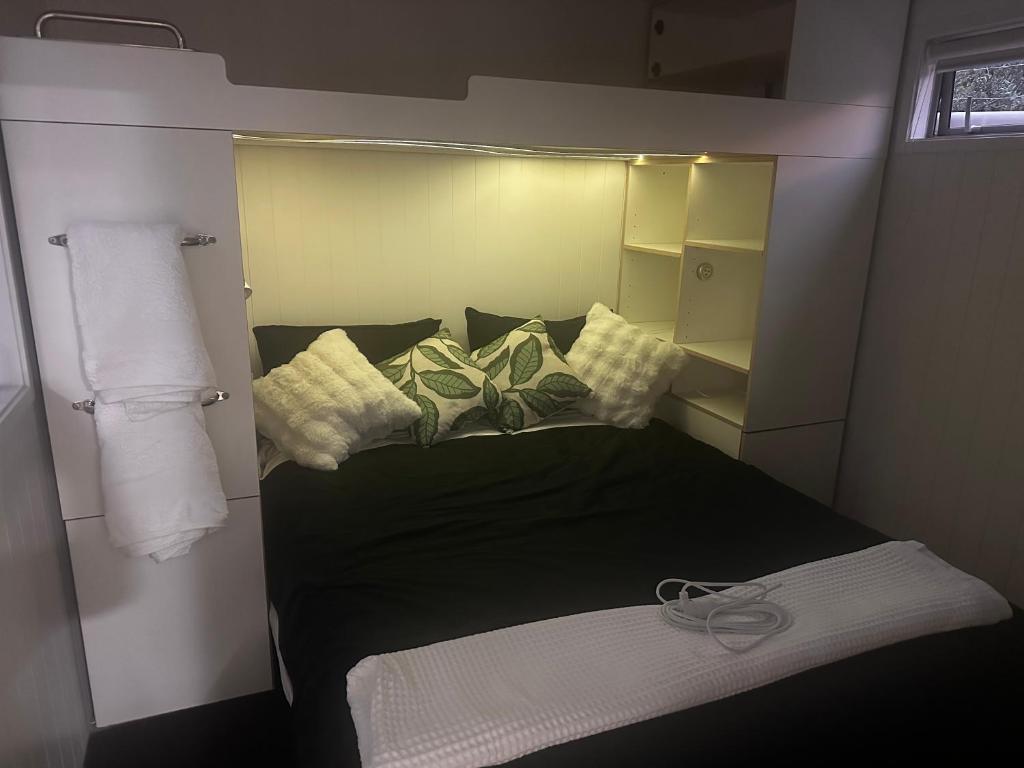 a small bed in a small room with towels at Kauri Cabin in Gisborne