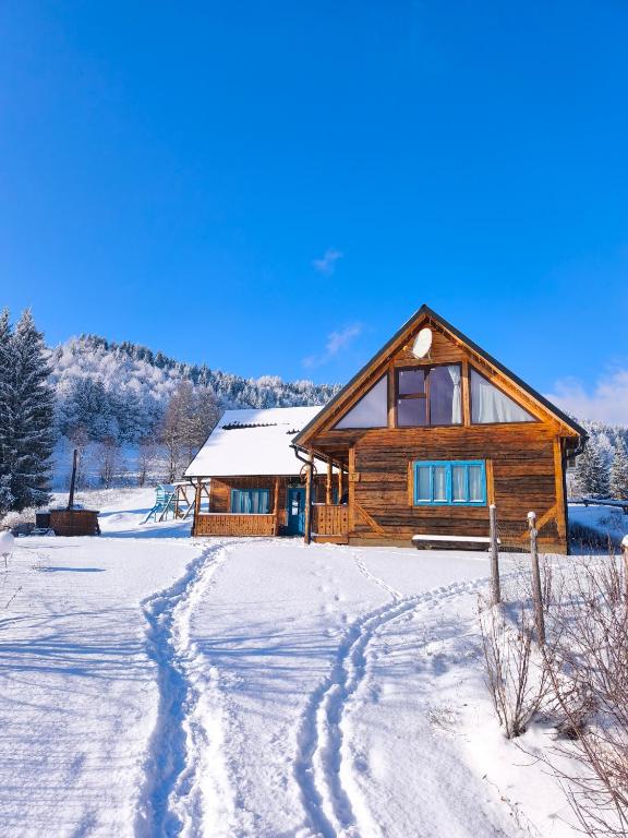 a log cabin in the snow with a trail at Căsuța de la munte in Bistriţa