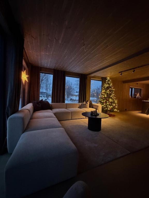 a living room with a large couch and a christmas tree at Exclusive Cabin with Sauna in Fossmo