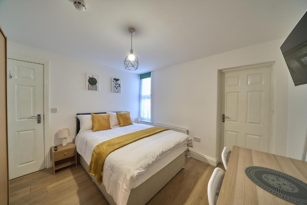 a white bedroom with a bed and a table at Chapel Road Cosy Rooms & Studios in Hounslow