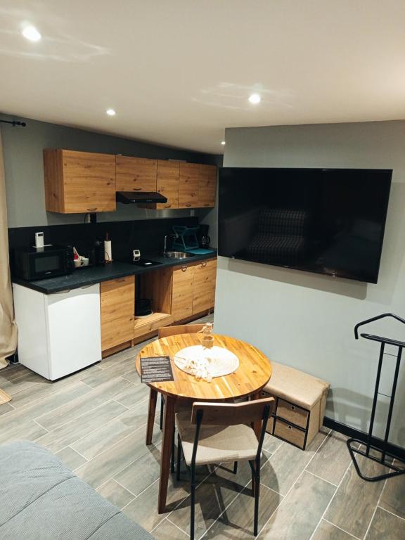 a living room with a table and a kitchen at Studio cosy in Auby