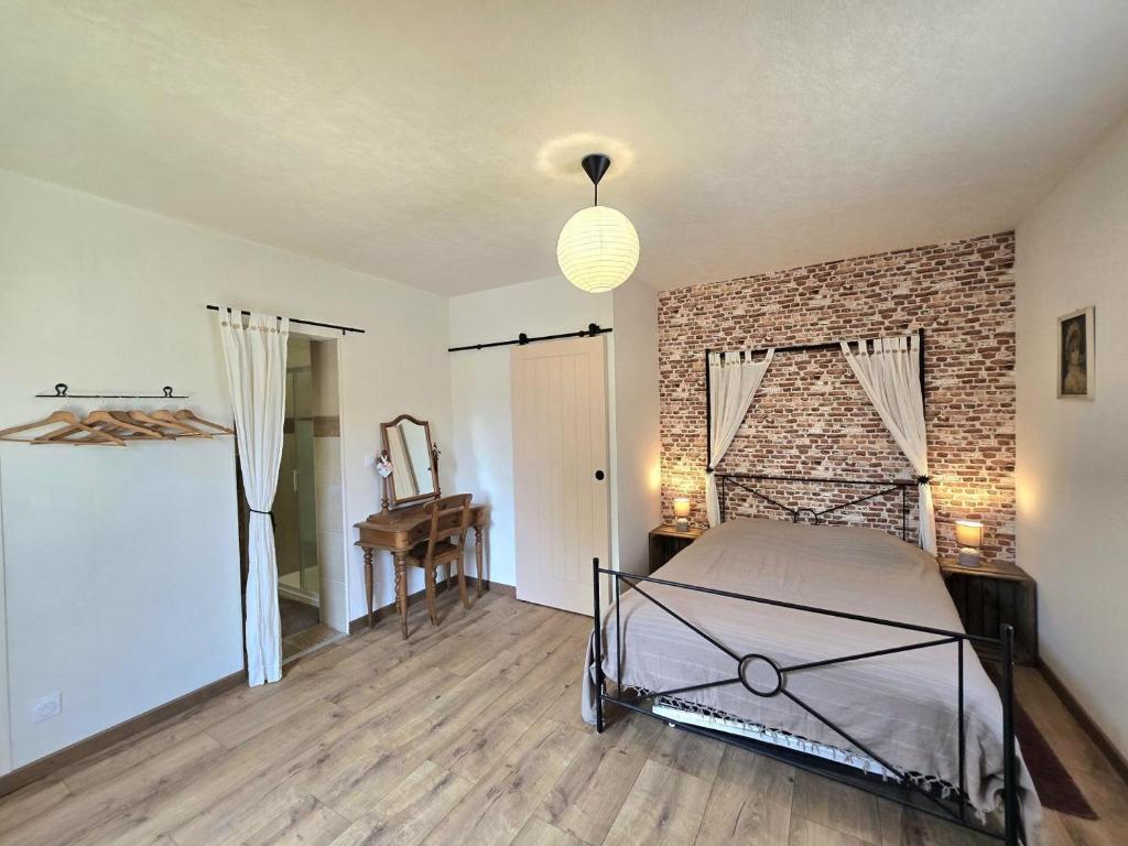 une chambre avec un lit et un mur de briques dans l'établissement Jonadam, à Saint-Julien-de-Lampon