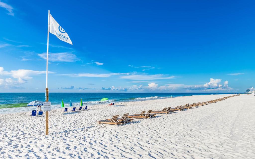 a beach with a flag and chairs and the ocean at Phoenix East 1405 in Orange Beach