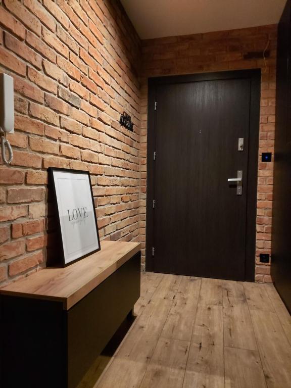 a black door in a brick room with a picture on a counter at Apartament 20 in Mysłowice