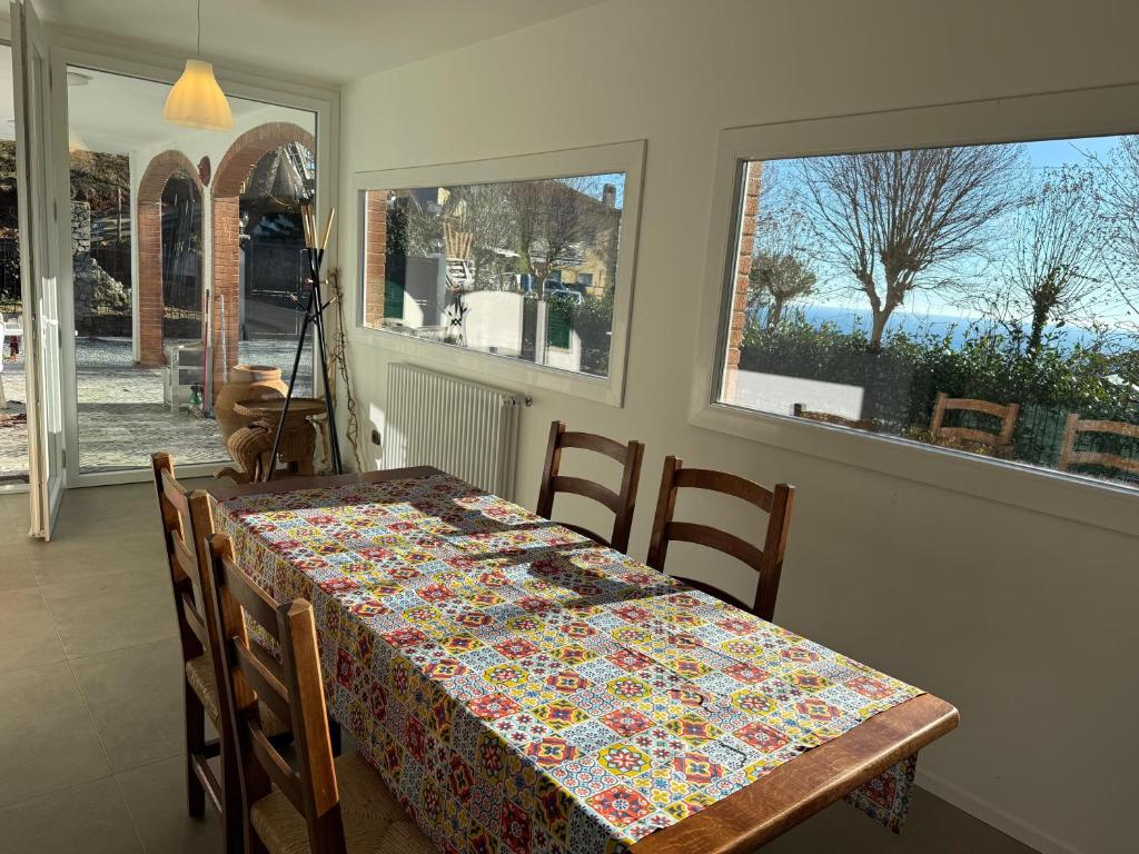 a dining room with a table and chairs and windows at Villetta Brasi in Celle Ligure