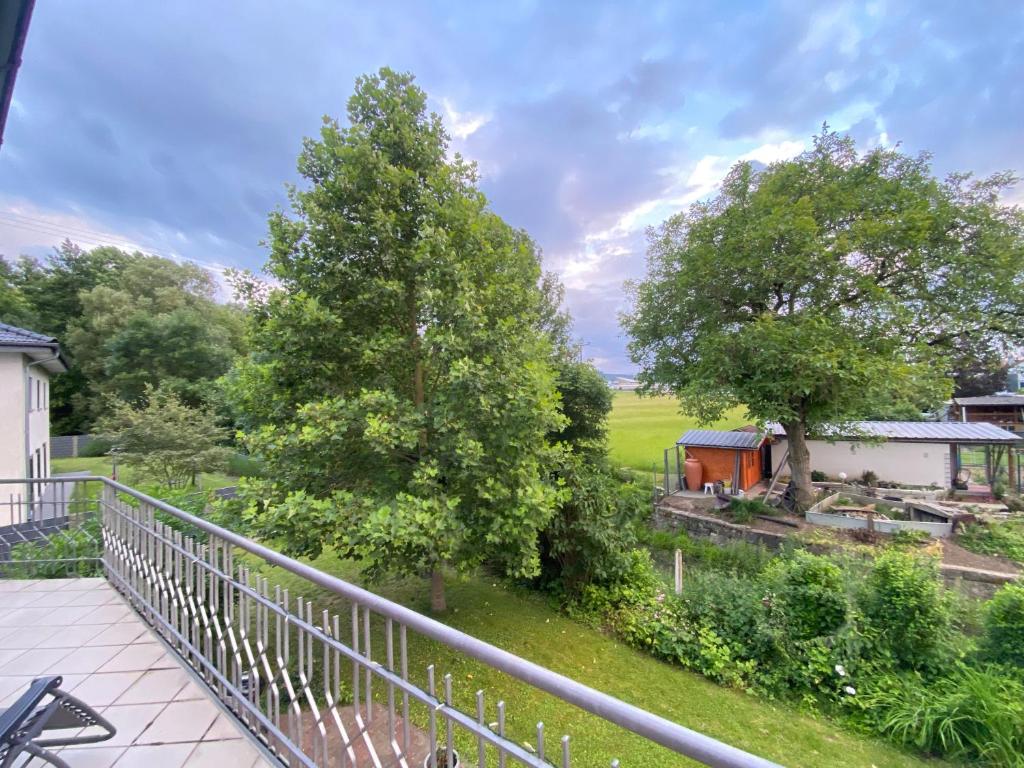 uitzicht op de tuin vanaf het balkon van een huis bij Pension Zum Waldrand in Sinsheim
