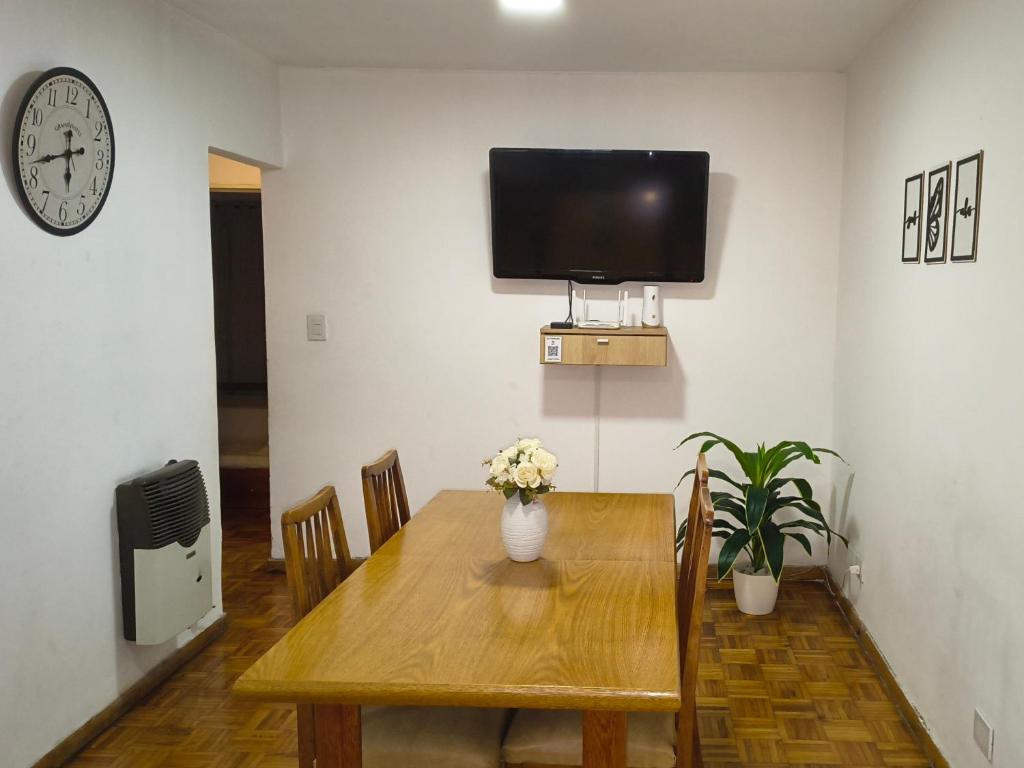 een eetkamer met een houten tafel en een tv aan de muur bij La Victoria in Rosario