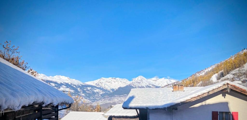 un tetto innevato di un edificio con montagne sullo sfondo di Chalet Le Monastère a Nendaz